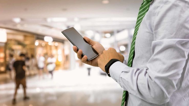 Mann mit Handy im Einkaufszentrum